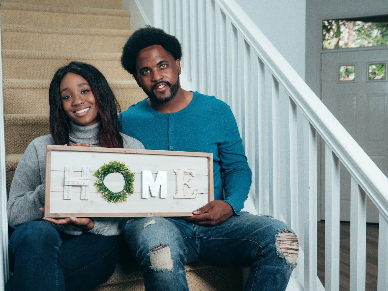 Couple holding a "Home" Sign