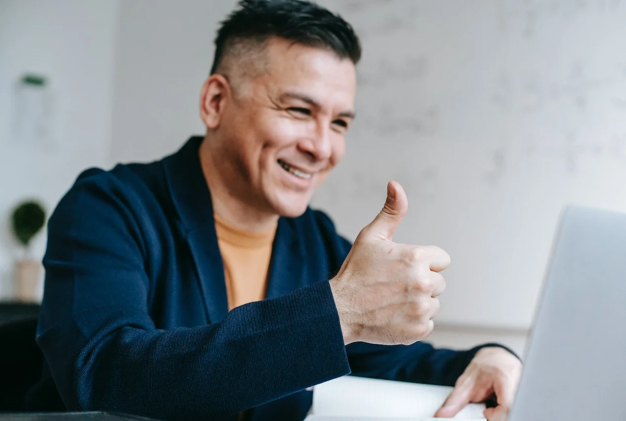 Man looking at screen giving a thumbsup