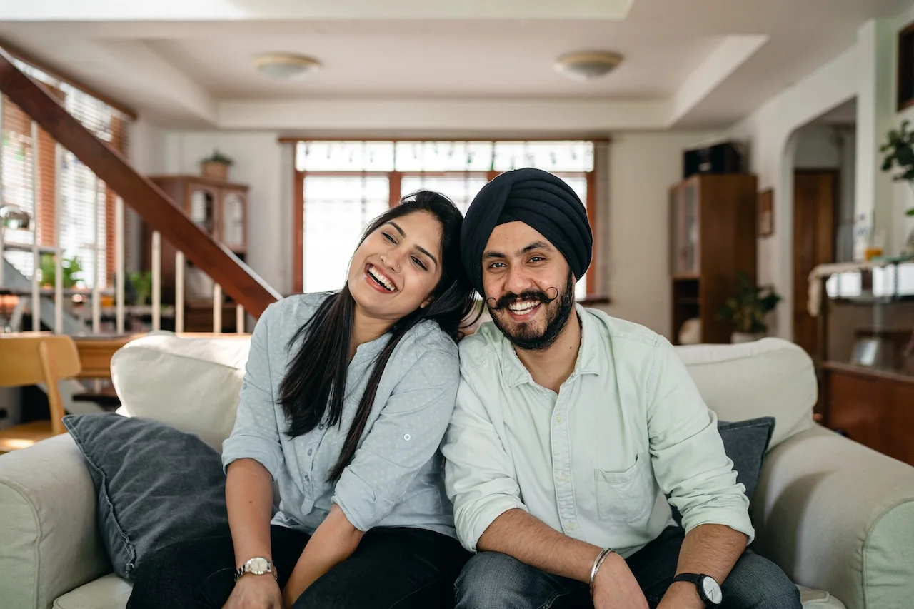 Indian couple on a couch smiling and happy