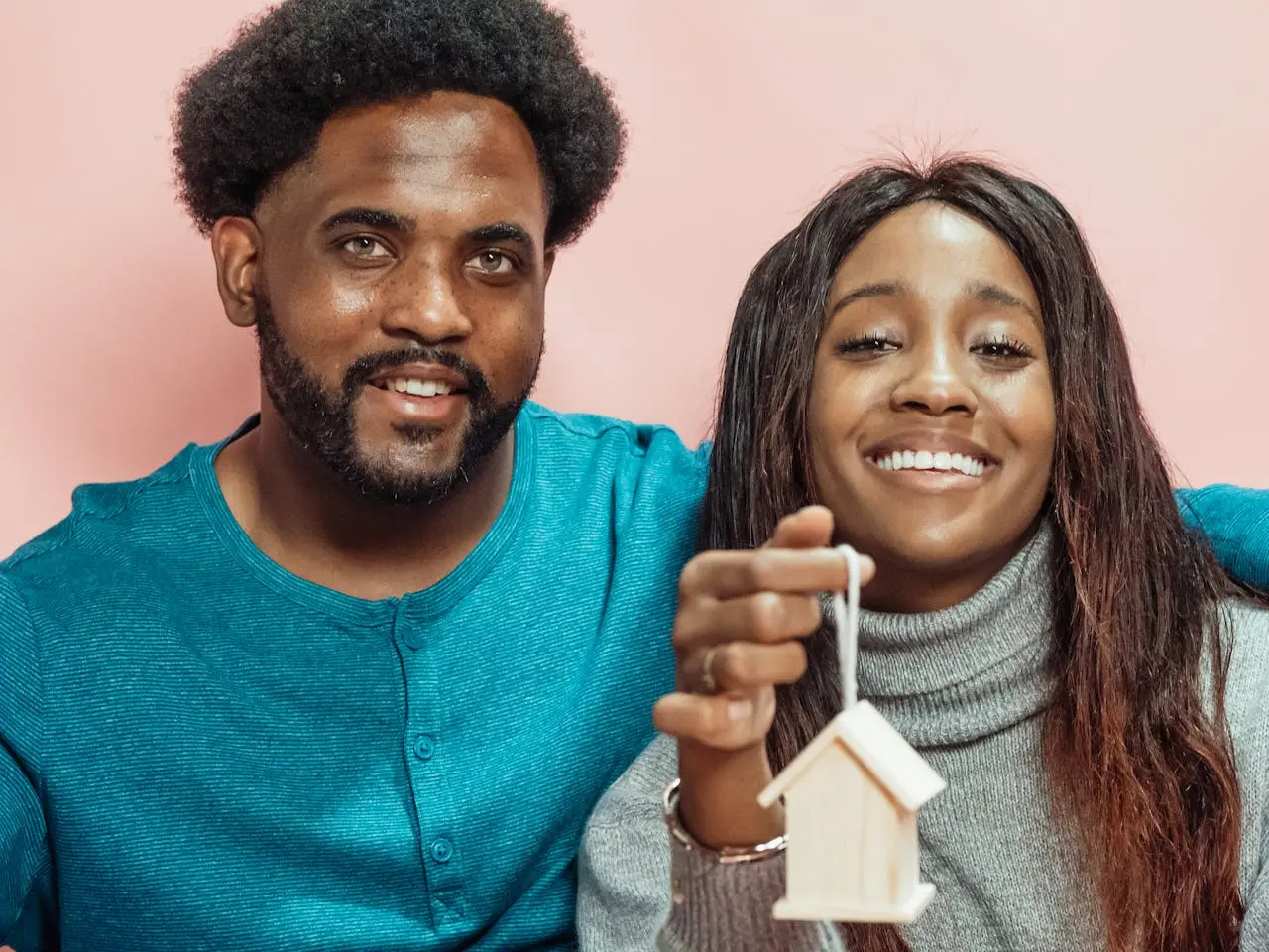 Happy Brown couple holding a 3d model of a home